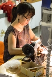 This is a chain stitch embroidery machine (one of the oldest machines still in use) making letters on felt.  The operator is moving the fabric with a lever UNDER the table.