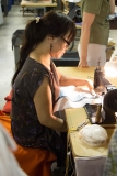 This is a chain stitch embroidery machine (one of the oldest machines still in use) making letters on felt.  The operator is moving the fabric with a lever UNDER the table.